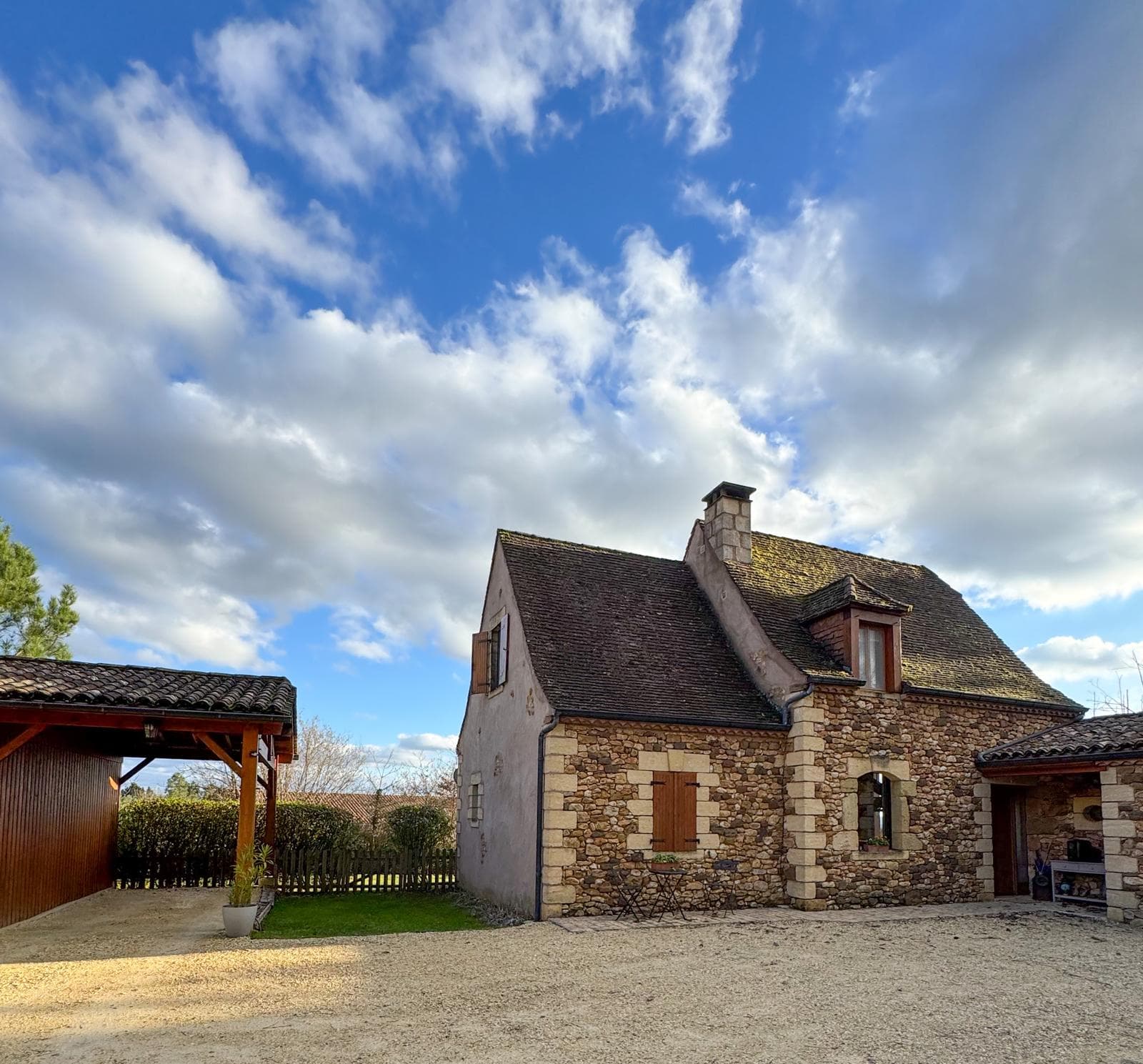 Huis van natuursteen in de Périgord onder een blauwe lucht met wolken